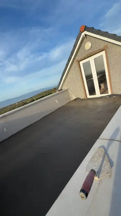 A freshly poured balcony floor with a trowel on the edge, looking out to the lough