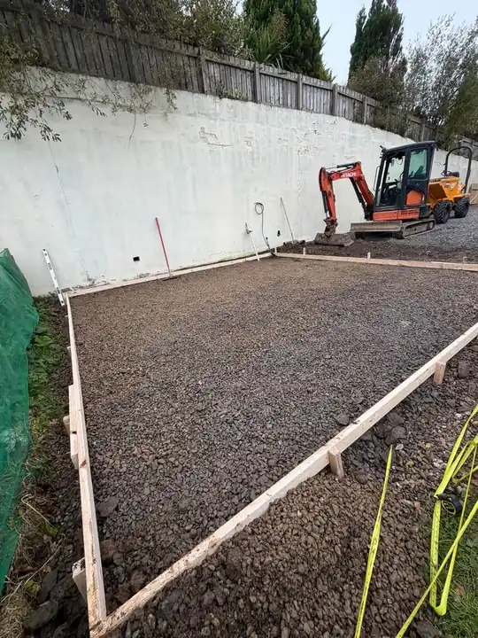 A shed base dug out and shuttered, with a mini digger behind